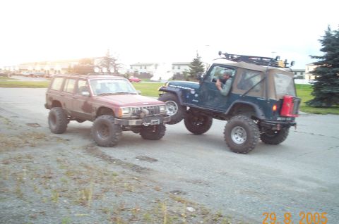1988 Jeep Cherokee - A lifted 1988 Jeep Cherokee is parked next to a blue Jeep Wrangler, both modified for off-road use.