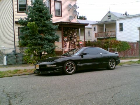 1997 Ford Probe - A black coupe is parked on a residential street with houses and trees visible.