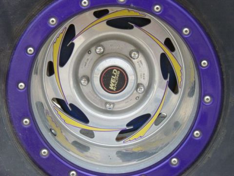 1990 Ford Bronco - A Weld Racing wheel with a purple beadlock and yellow flame graphics is shown up close.