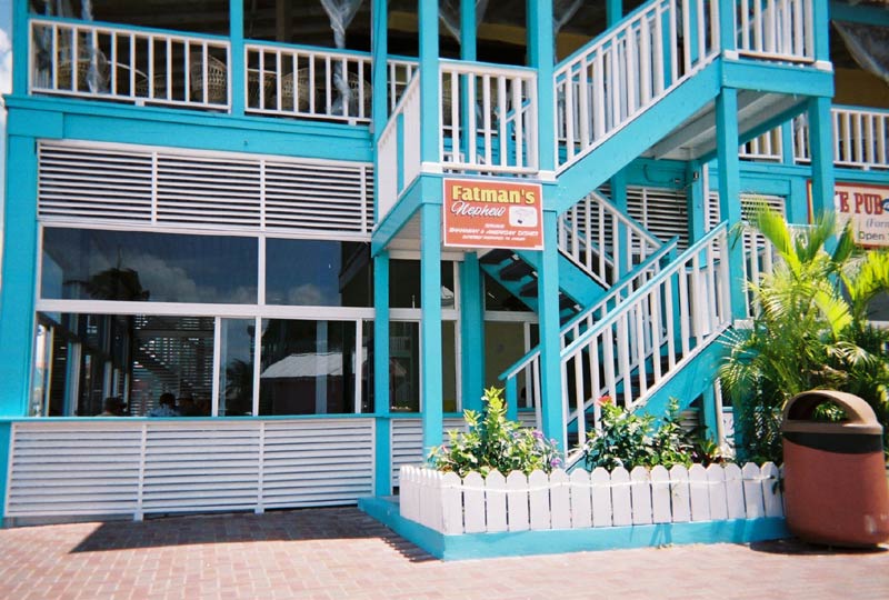 Blue and white building with outdoor stairs, a trash can, and a sign for Fatman's Nephew