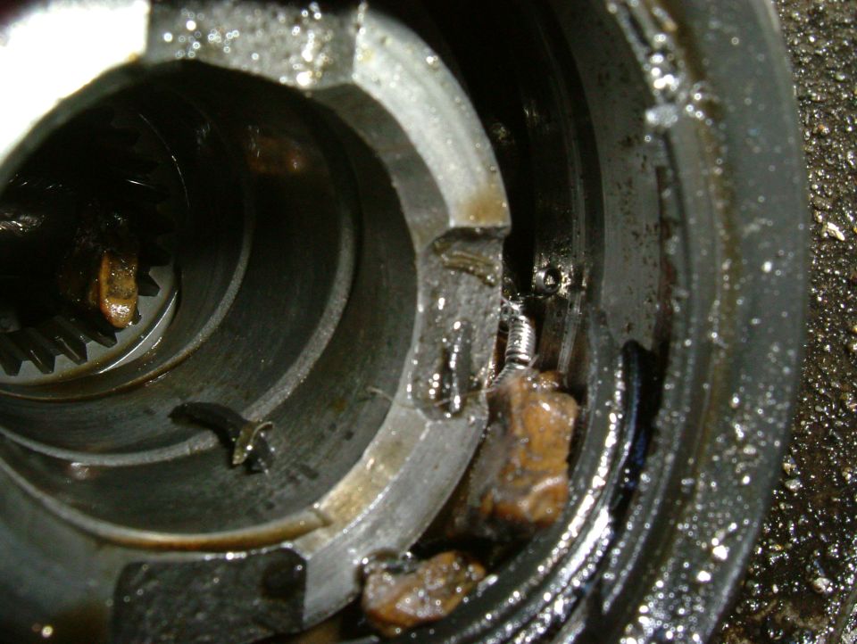 Close-up of a damaged internal mechanical component with gears and broken pieces visible