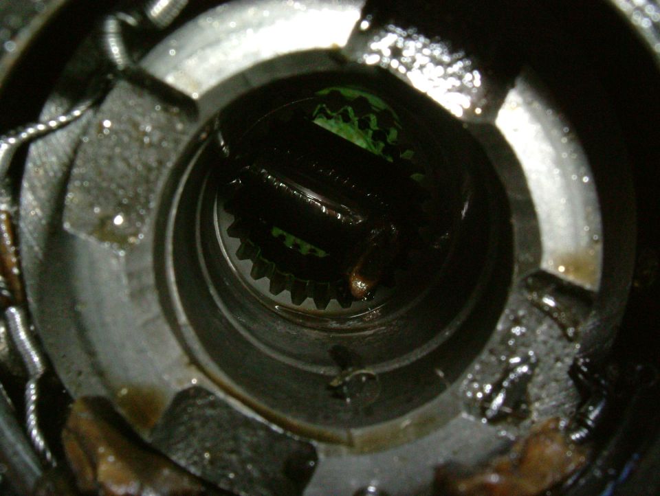 Close-up of a greasy, internal gear mechanism with visible teeth and springs