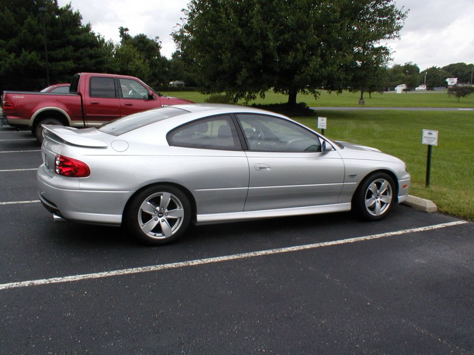 Silver coupe parked in a lot, side view
