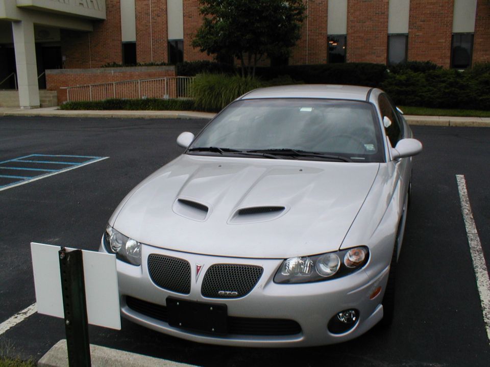Silver Pontiac GTO with hood scoops parked in a lot