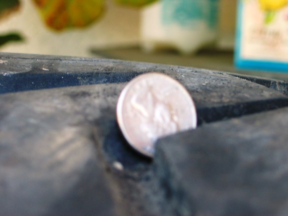 Silver coin balanced on edge in a groove of a dark gray surface