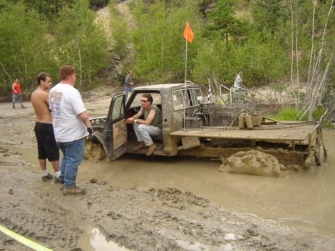 1987 Suzuki Samurai - A heavily modified pickup truck is stuck in deep mud during an off-road event.