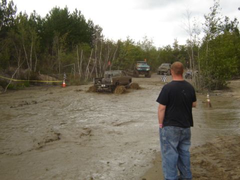 1987 Suzuki Samurai - Several off-road vehicles navigate a muddy course, with one Suzuki Samurai deeply mired in the muck.