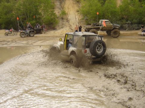 1987 Suzuki Samurai - Off-road vehicles tackle a muddy obstacle course during an event.