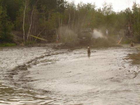 1987 Suzuki Samurai - A vehicle navigates a muddy track, spraying dirt and water.