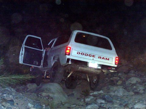 1981 Ford F-150 - A white Dodge Ram is shown off-roading on a rocky path at night, with its doors open.