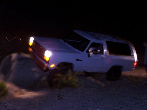1981 Ford F-150 - White SUV navigating rocky terrain at night with headlights illuminated.