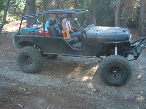 1964 Jeep CJ5 - This modified Jeep features a roll cage and oversized tires, suggesting it is built for off-road use.