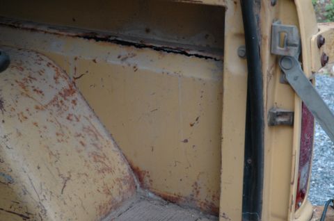 1972 Ford Bronco - The interior cargo area of a 1972 Ford Bronco displays significant rust and wear, particularly along the wheel well and door jamb.