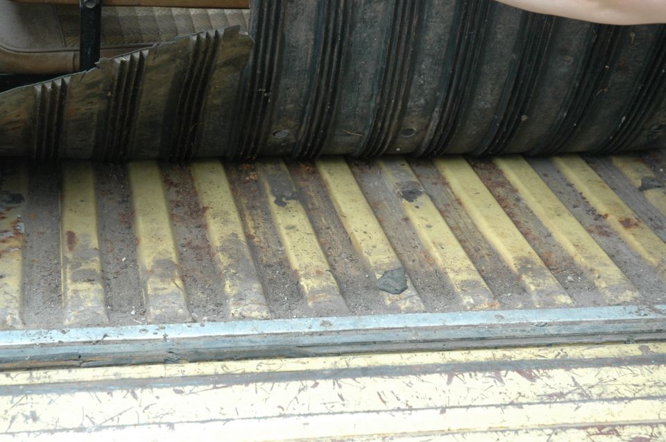 Corrugated metal floor of a vehicle with a lifted rubber mat
