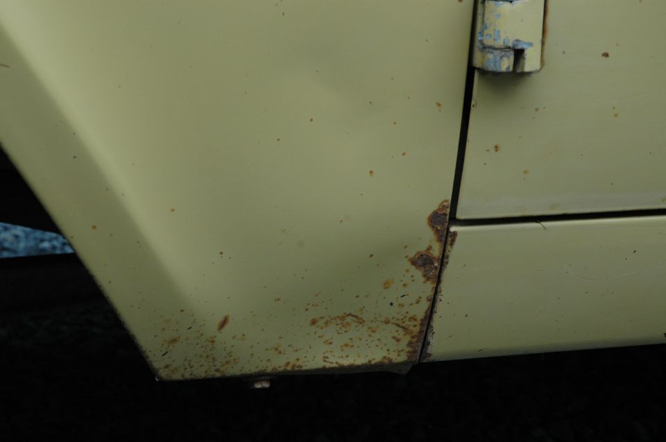 Close-up of a rusted seam on a light yellow vehicle door