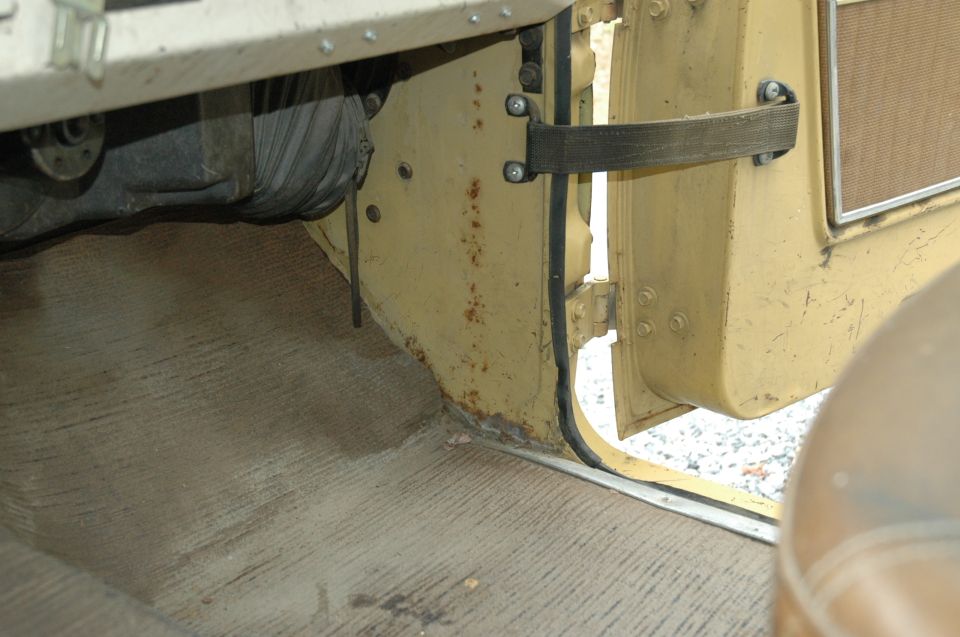 close-up of yellow vehicle's interior door sill with rust and worn carpet