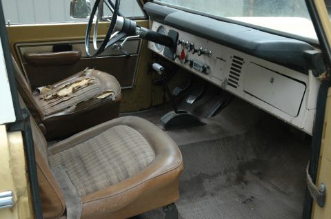 1972 Ford Bronco - The interior of a 1972 Ford Bronco shows its aged condition with torn driver's seat and worn floor mats.