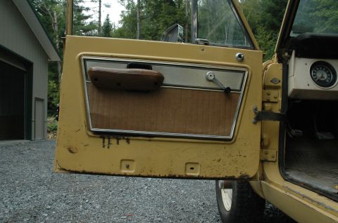 1972 Ford Bronco - Close-up of the driver's side interior of a vintage vehicle, showing the door panel and part of the dashboard.