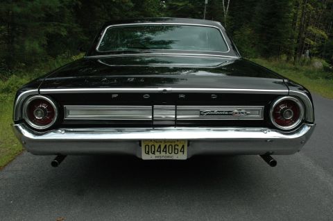 1964 Ford Galaxie - The rear of a black 1964 Ford Galaxie 500XL is shown, chrome trim and dual exhaust pipes.