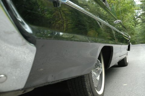 1964 Ford Galaxie - A close-up of the lower body and rear wheel of a vintage automobile parked on a road.