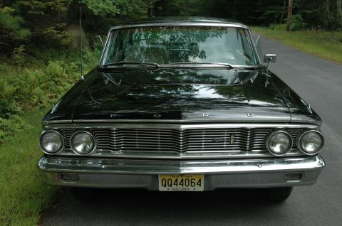 1964 Ford Galaxie - A black 1964 Ford Galaxie 500XL is shown from the front, parked on the side of a road.
