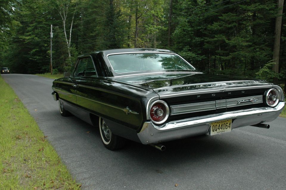 Black 1964 Ford Galaxie two-door hardtop, rear 3/4 view on wooded road
