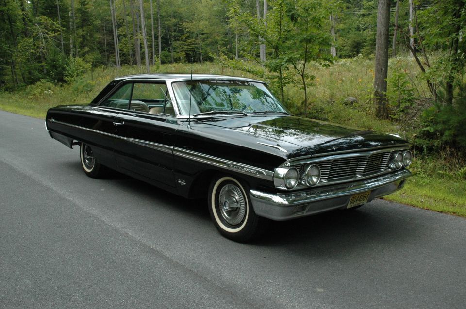 Black 1964 Ford Galaxie coupe, front 3/4 view on a wooded road