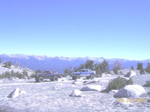 1994 Ford Bronco - Two trucks are parked on a rocky, high-altitude road with mountains visible in the distance.