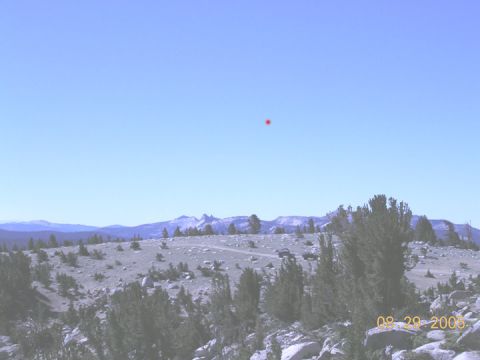 1994 Ford Bronco - Two SUVs are visible on a dirt road in a vast, rocky, mountainous terrain on a clear day.