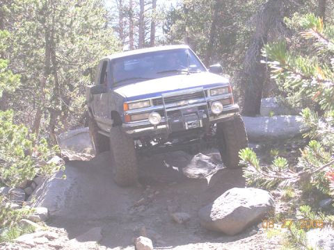 1994 Ford Bronco - A blue pickup truck is shown off-roading on a rocky trail.