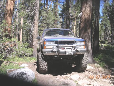 1994 Ford Bronco - A blue pickup truck is parked on a rocky trail surrounded by trees. The date 08.27.2005 is visible in the lower right corner.