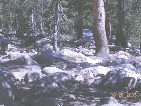 1994 Ford Bronco - A blue SUV is parked on a rough, rocky trail surrounded by trees. The date 08.26.2005 is visible.