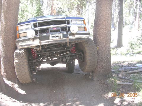 1994 Ford Bronco - This truck appears to be stuck between two trees on a wooded trail, with its front tires off the ground.
