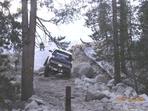 1994 Ford Bronco - Chevrolet pickup truck tackling a challenging rocky trail with a person observing in the distance.