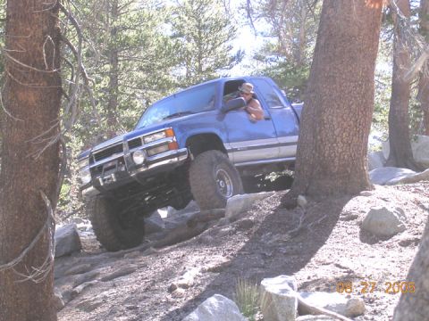 1994 Ford Bronco - A blue GMC pickup truck is shown off-roading on a rocky, wooded trail on August 27, 2005.