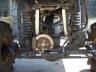 1990 Ford Bronco - A close-up shot reveals the complex mechanicals of a vehicle's undercarriage, focusing on suspension and drivetrain.