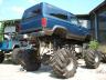 1990 Ford Bronco - A blue monster truck is parked outdoors, with another vehicle visible in the background.
