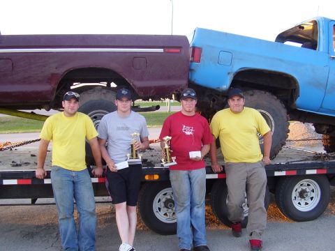 1979 Ford F-250 - Four men pose with trophies next to two lifted trucks on a trailer.