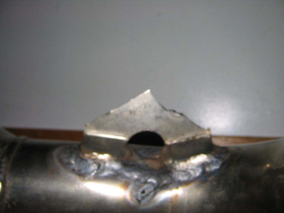 Metal mounting tab with a drilled hole welded onto a polished steel tube.