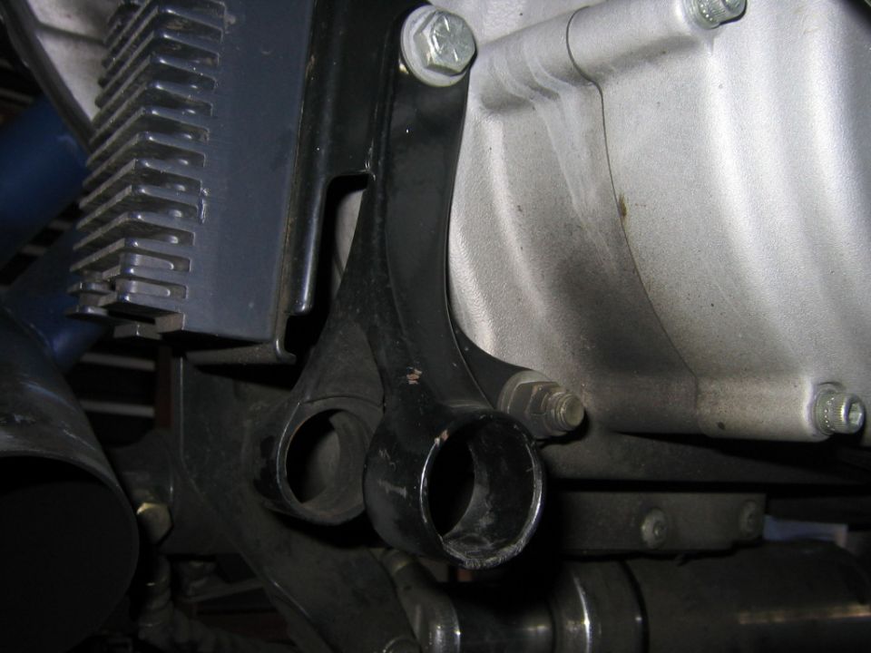 Close-up of a black metal bracket attached to a silver engine casing