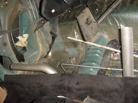 1995 Ford Mustang - The interior of a car shows green metal panels, black seatbelts, and an exhaust pipe.