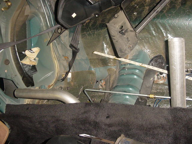 Car interior showing green metal panels, black seatbelts, and exhaust pipe