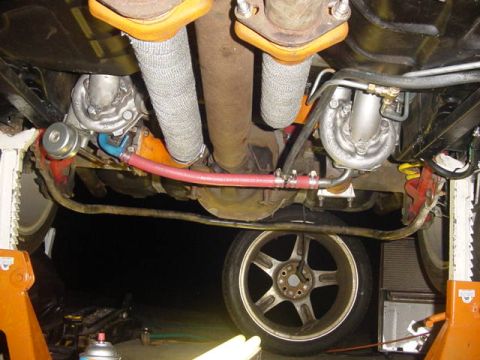 1995 Ford Mustang - The underside of a vehicle reveals a twin-turbocharged engine setup with exhaust components and suspension visible.