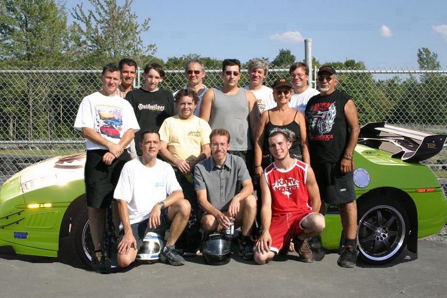 group of people posing with a bright green race car that has a large rear spoiler