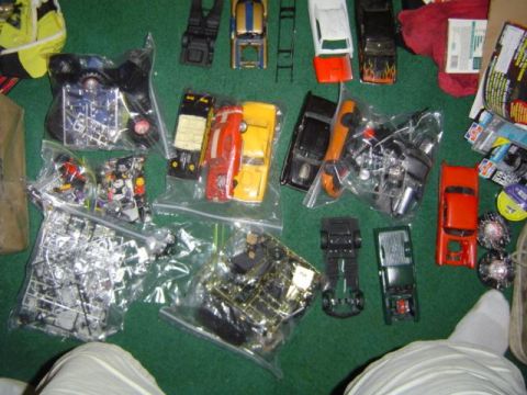 1979 Ford Bronco - Various unassembled model car kits and individual parts are laid out on a green surface, suggesting a hobbyist's collection.