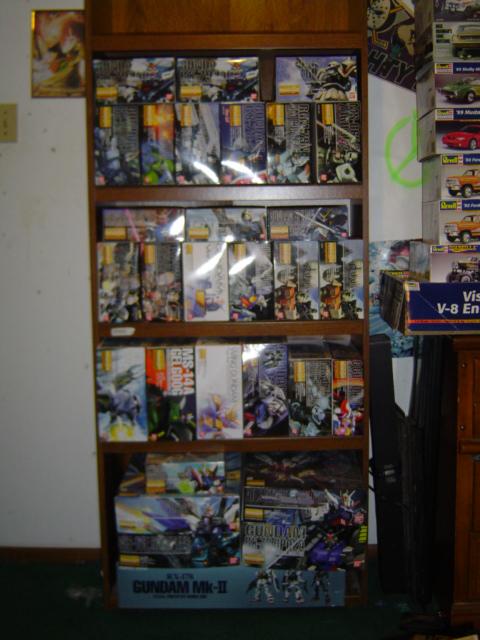 1979 Ford Bronco - A collection of model kits, primarily Gundam, are neatly organized on wooden shelves.