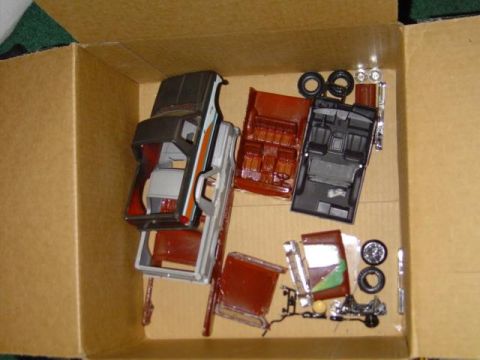 1979 Ford Bronco - Unassembled model kit parts are laid out in a cardboard box, showing various components for a vehicle.