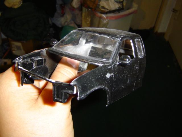 Black model truck cab held in hand, front end missing