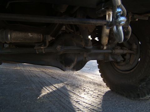 1988 Ford Bronco - The underside of a vehicle reveals its mechanical components, including the front axle and suspension system.