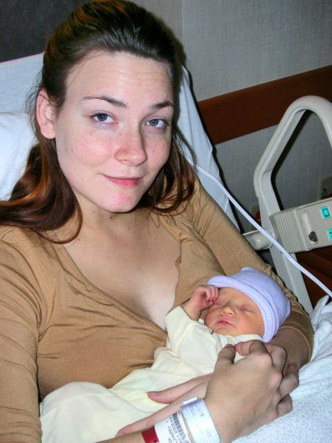2003 Jeep TJ - A woman smiles while holding her newborn baby in a hospital room.